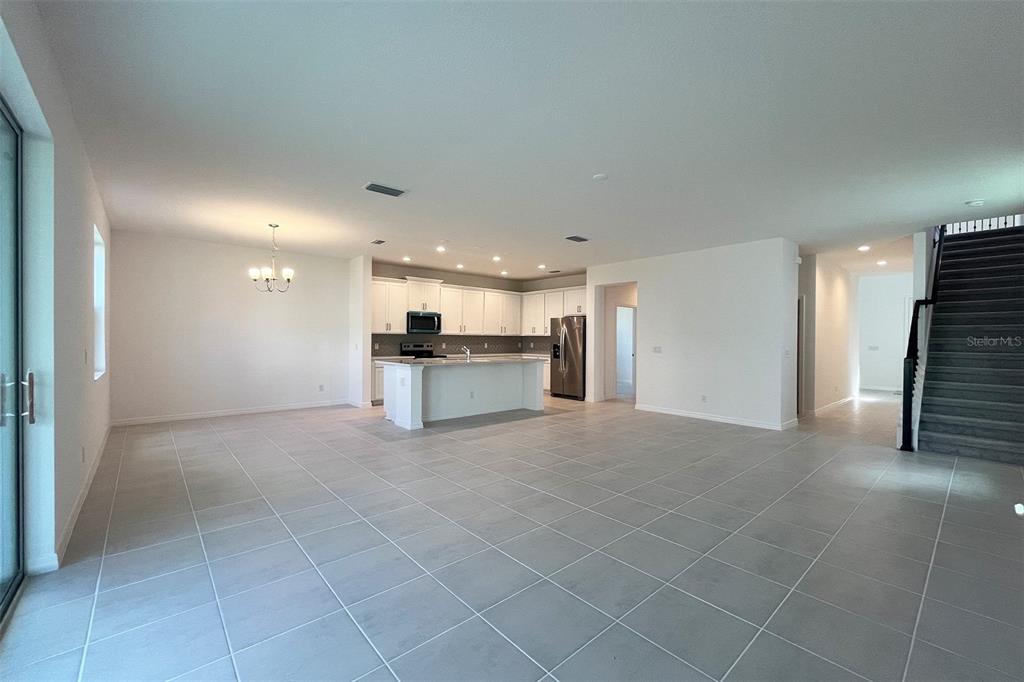 An open-concept kitchen and living area features white cabinetry, a central island, and tile flooring — 7052 ROLLING LEAF ROAD, GROVELAND, FL