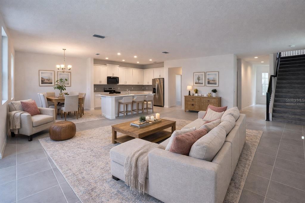 An open-concept living room, dining area, and kitchen with white cabinetry and tile flooring — 7052 ROLLING LEAF ROAD, GROVELAND, FL