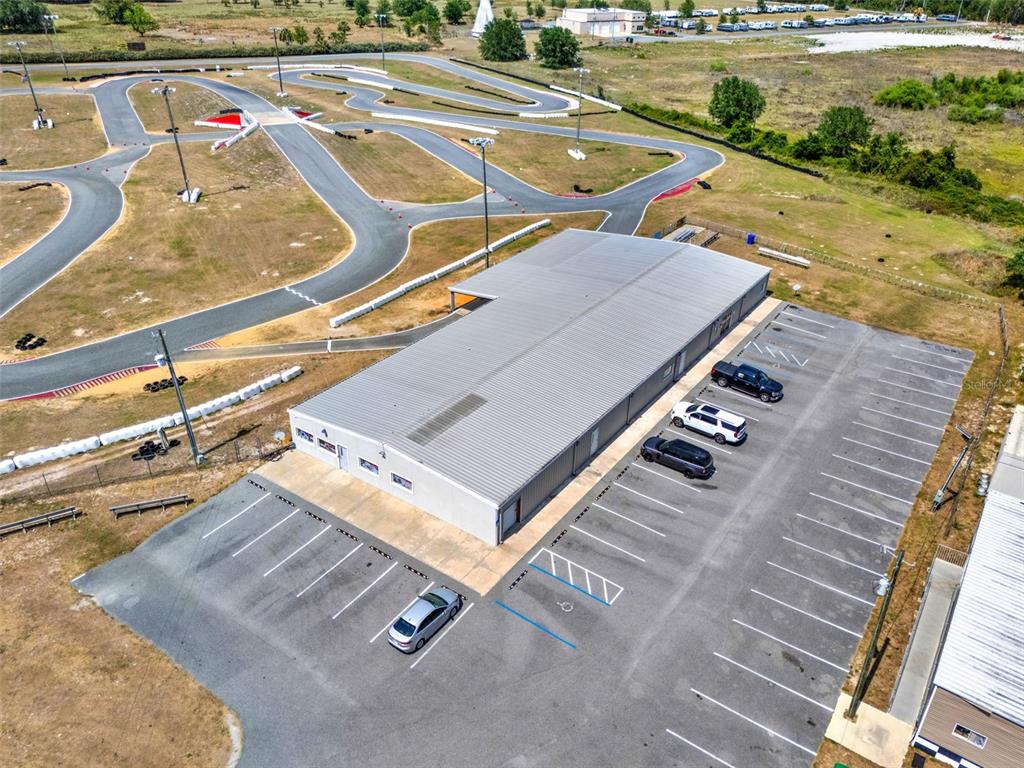 An aerial view shows a rectangular metal building with a parking lot and a go-kart track — 5821 PIT ROAD, BUSHNELL, FL