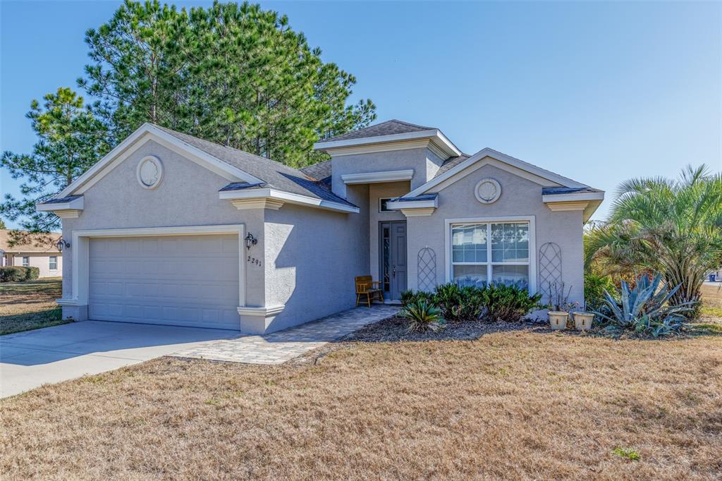 A single-story stucco house with a two-car garage and a paved walkway to the entrance — 2291 N MIA POINT, LECANTO, FL