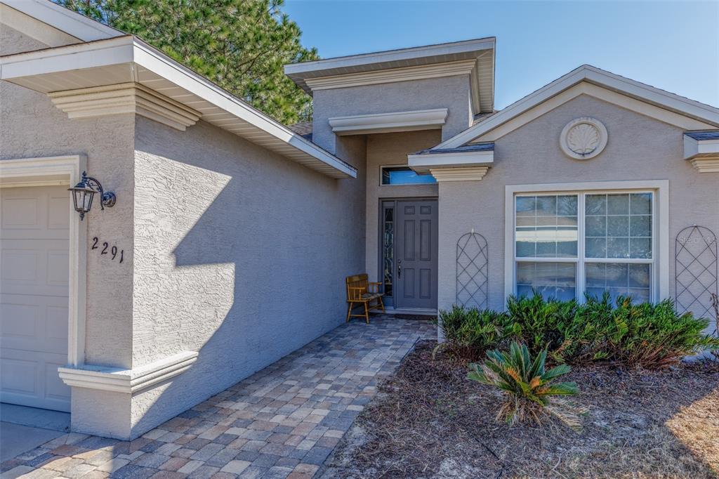 A single-story house exterior features a paved walkway, a gray front door, and a garage — 2291 N MIA POINT, LECANTO, FL