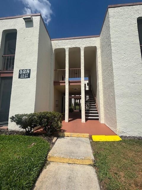 A two-story apartment building exterior features a central staircase and a concrete walkway — 528 ORANGE DRIVE UNIT 26, ALTAMONTE SPRINGS, FL