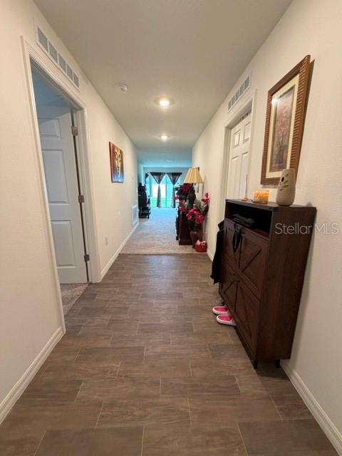 A hallway with wood-look tile flooring leads to a living area with sliding glass doors — 2776 SW 164TH STREET ROAD, OCALA, FL