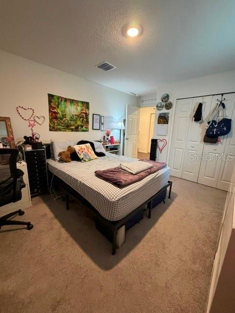 A bedroom features a bed with a checkered comforter, carpeted flooring, and white closet doors — 2776 SW 164TH STREET ROAD, OCALA, FL