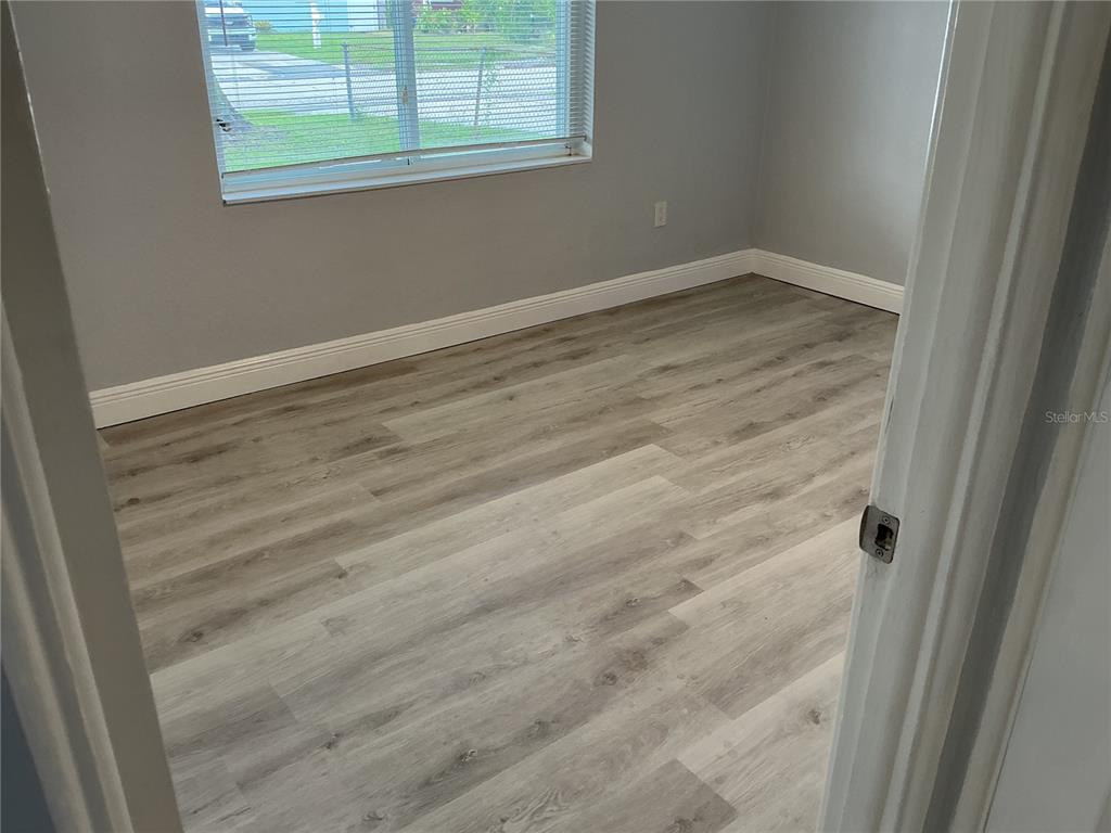 An empty bedroom features light gray walls, white baseboards, and wood-look vinyl plank flooring — 4660 71ST AVENUE N, PINELLAS PARK, FL
