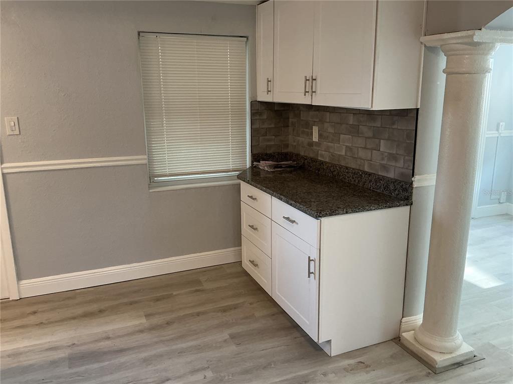 A kitchen area features white cabinets, a dark granite countertop, and a gray tile backsplash — 4660 71ST AVENUE N, PINELLAS PARK, FL