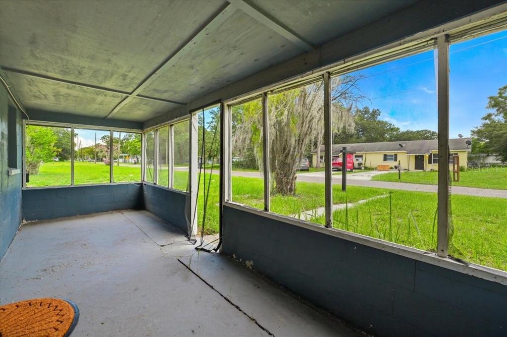 A screened-in porch with a concrete floor, blue painted walls, and views of a neighborhood — 2418 JUNGLE STREET, LAKELAND, FL