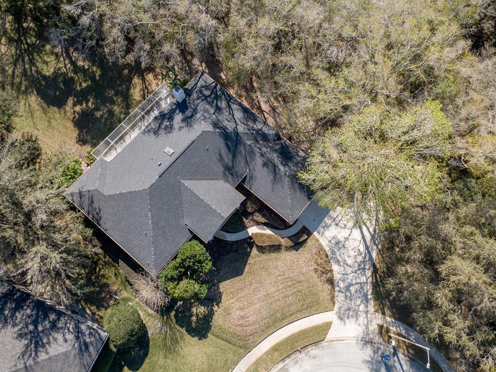 An aerial view shows a house with a dark shingled roof and a screened-in patio — 814 BRANTENBURG WAY, LUTZ, FL