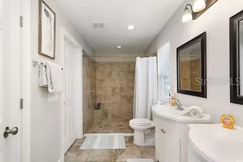 A bathroom features a walk-in tiled shower, a white vanity with a mirror, and a toilet — 305 LINDEN DRIVE, ELLENTON, FL