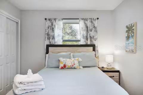 A bedroom features a bed with light blue bedding, a wooden headboard, and patterned curtains — 305 LINDEN DRIVE, ELLENTON, FL