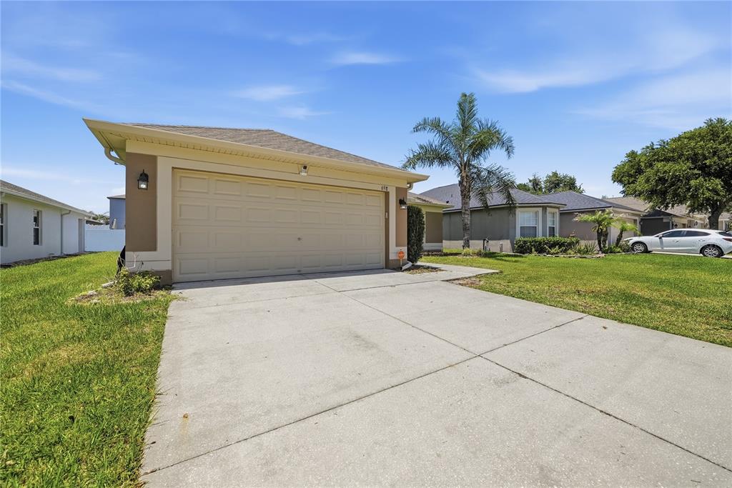 A beige house features a two-car garage, a concrete driveway, and a palm tree — 698 WINTHROP DRIVE, SPRING HILL, FL