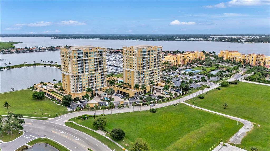 An aerial view shows two tall residential buildings situated near a marina and water — 130 RIVIERA DUNES WAY UNIT 701, PALMETTO, FL
