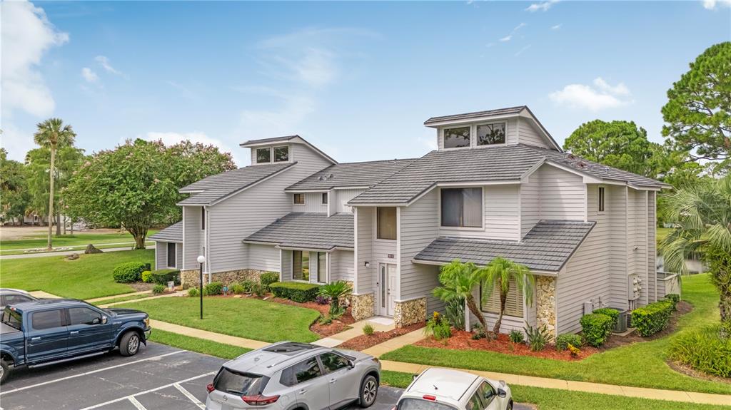 An exterior view of a multi-story gray siding townhouse with a dark shingled roof — 150 BLUE HERON DRIVE UNIT B, DAYTONA BEACH, FL