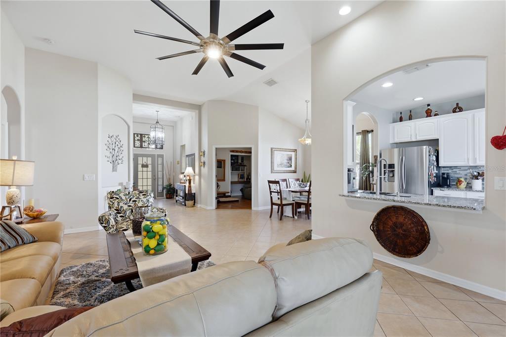 A living room with a ceiling fan opens to a kitchen with white cabinets — 5310 72ND STREET E, PALMETTO, FL