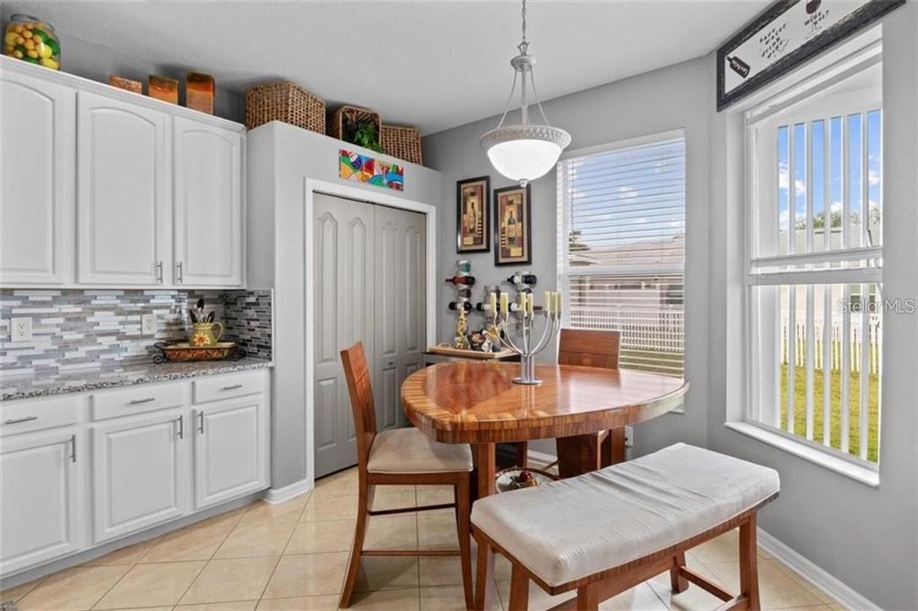 A kitchen dining area with white cabinets, a wooden table, a bench, and a window — 5310 72ND STREET E, PALMETTO, FL