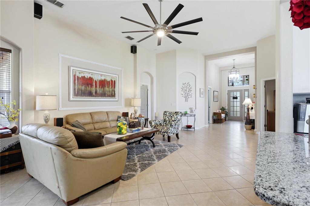 A living room features beige leather sofas, a patterned armchair, and a large ceiling fan — 5310 72ND STREET E, PALMETTO, FL