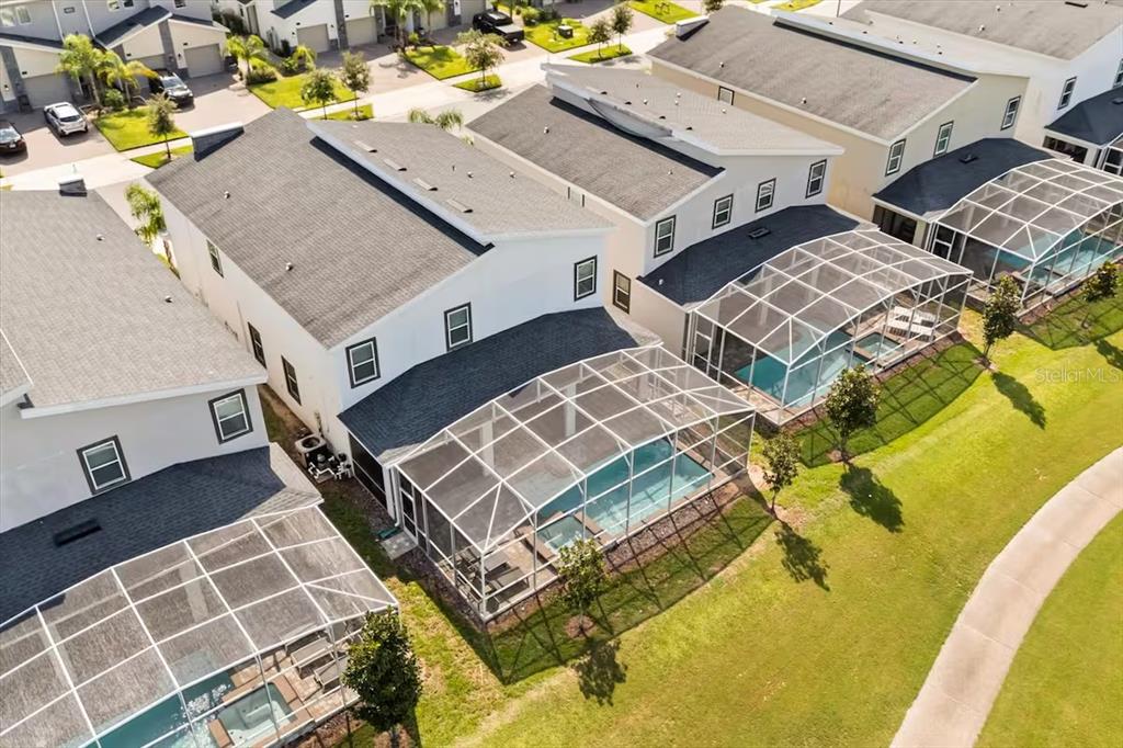 An aerial view shows several suburban houses with screened-in swimming pools and grassy backyards — 8882 CABOT CLIFFS DRIVE, DAVENPORT, FL