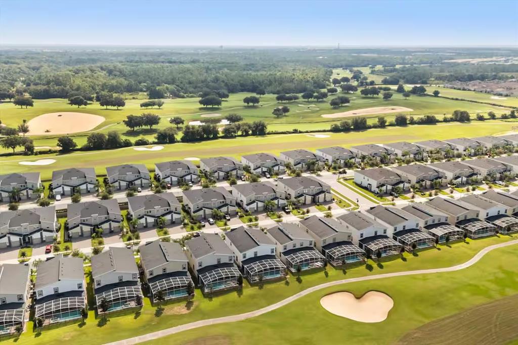 An aerial view shows rows of suburban houses adjacent to a golf course with sand traps — 8882 CABOT CLIFFS DRIVE, DAVENPORT, FL