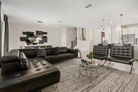 A modern open-concept living room features a large black sectional sofa and two matching chairs — 8882 CABOT CLIFFS DRIVE, DAVENPORT, FL