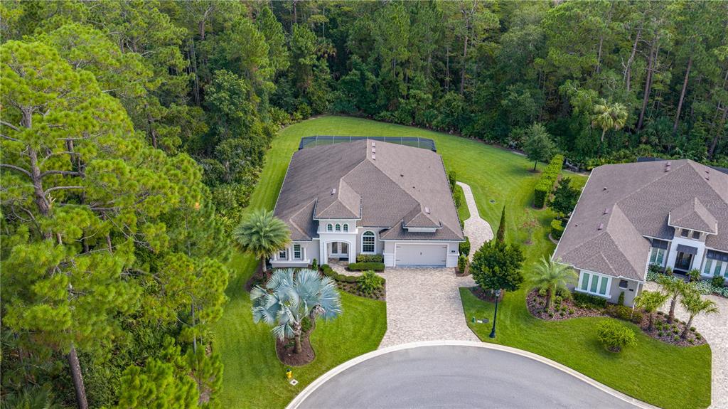 An aerial view shows a suburban house with a paved driveway and a screened-in backyard patio — 214 ASHWOOD COURT, ORMOND BEACH, FL
