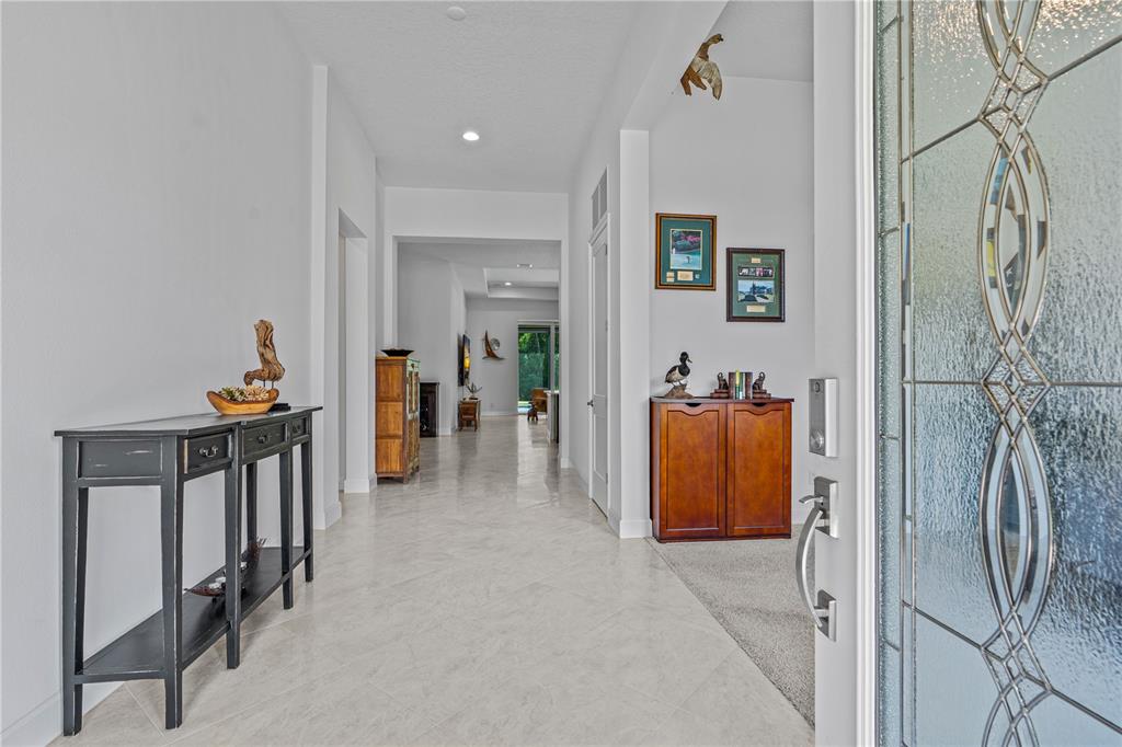 A bright entryway features light tile flooring, a black console table, and a wooden cabinet — 214 ASHWOOD COURT, ORMOND BEACH, FL