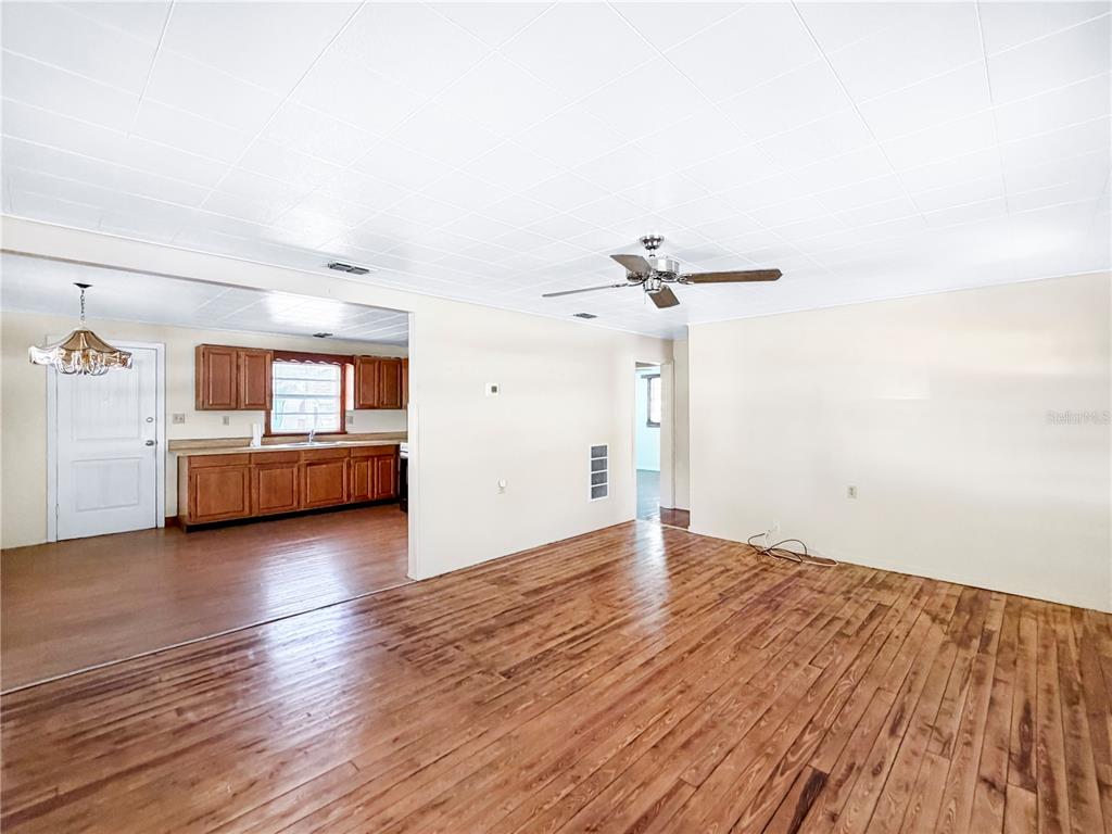 A living room with wood flooring and a ceiling fan opens into a kitchen area — 1455 10TH STREET NW, LARGO, FL