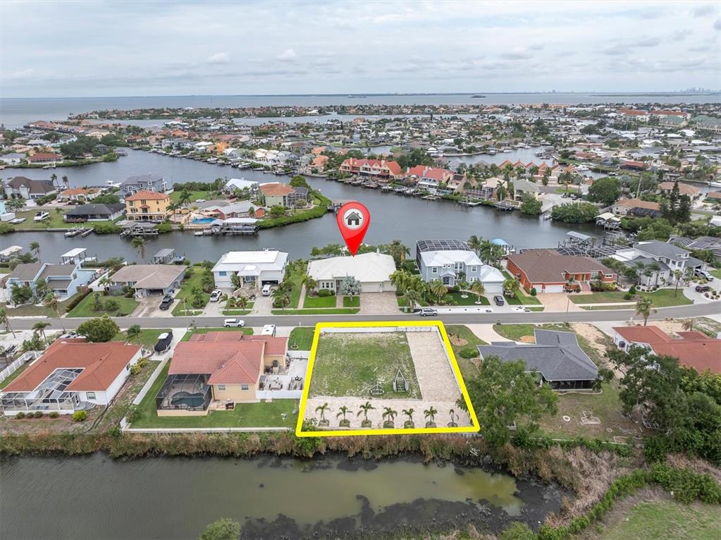 An aerial view shows a vacant waterfront lot outlined in yellow near residential homes — 811 BIRDIE WAY, APOLLO BEACH, FL