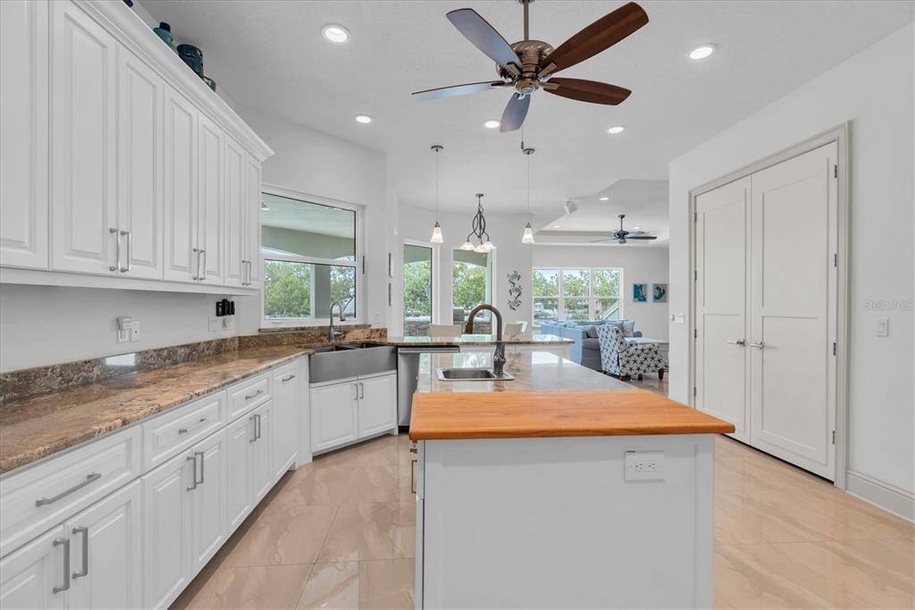 A white kitchen features a wooden island countertop, granite counters, and a ceiling fan — 811 BIRDIE WAY, APOLLO BEACH, FL