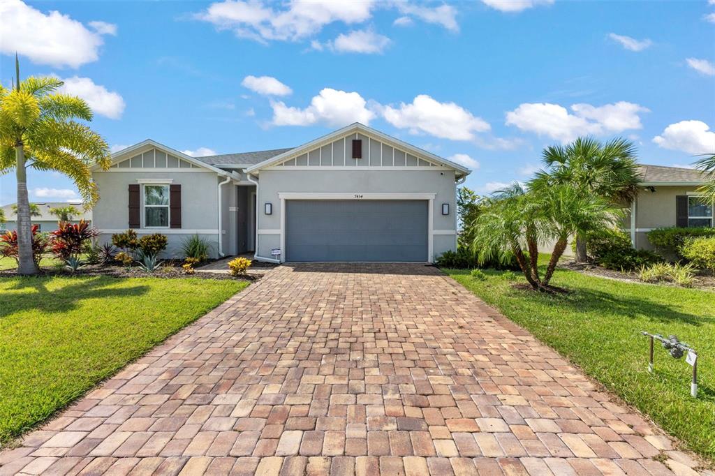 A single-story house with a paved driveway, a two-car garage, and palm trees — 7434 35TH LANE E, SARASOTA, FL