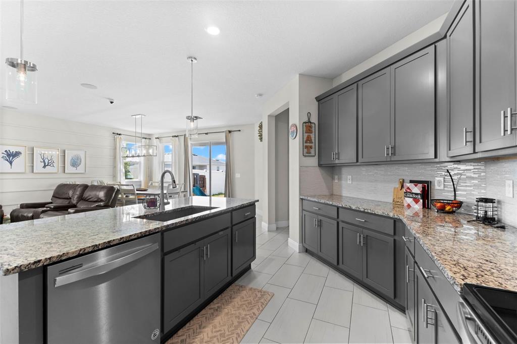 A kitchen features dark gray cabinets, granite countertops, a large island, and stainless steel appliances — 7434 35TH LANE E, SARASOTA, FL