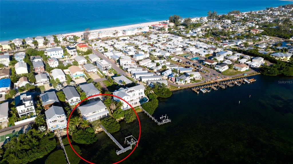 An aerial view shows a waterfront house with a private dock and surrounding vegetation — 2512 AVENUE A, BRADENTON BEACH, FL