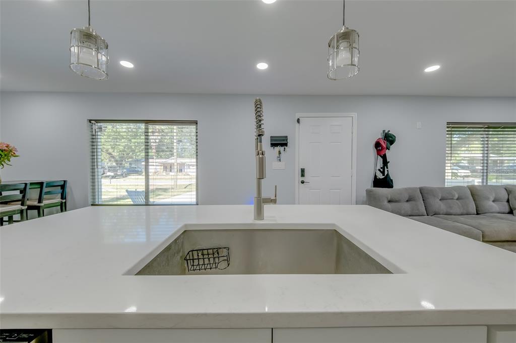 A kitchen island with a stainless steel sink and faucet faces a living area — 1814 SYLVAN DRIVE, CLEARWATER, FL