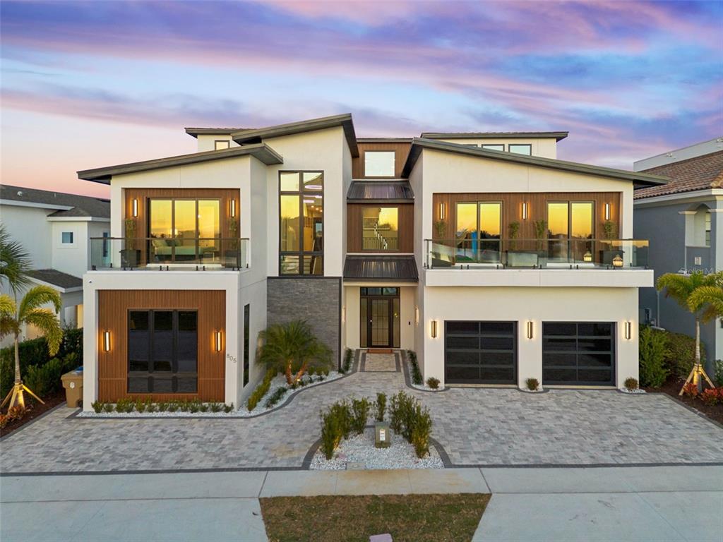 A modern two-story house features a white stucco exterior, wood accents, and a paved driveway — 805 GOLDEN BEAR DRIVE, REUNION, FL