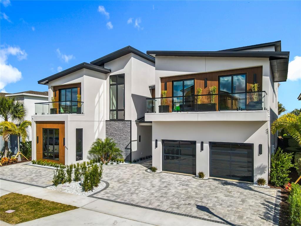 A modern two-story house features a paved driveway, a two-car garage, and upper-level balconies — 805 GOLDEN BEAR DRIVE, REUNION, FL