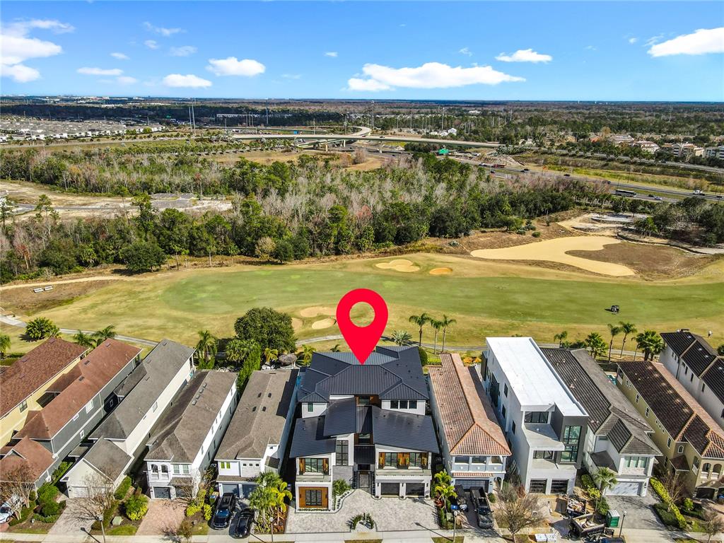 An aerial view shows a modern multi-story house situated along a golf course — 805 GOLDEN BEAR DRIVE, REUNION, FL