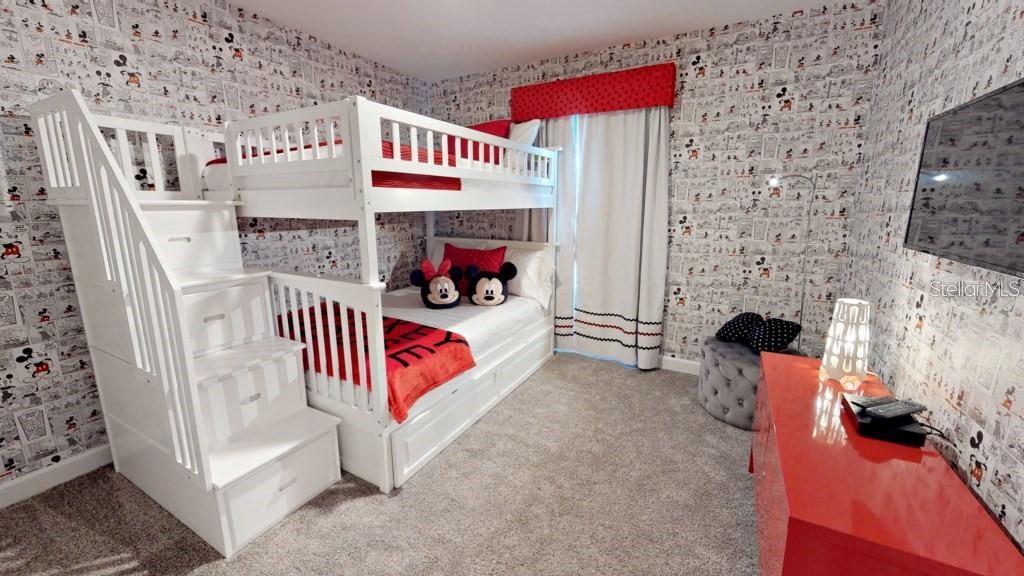 A bedroom features Mickey Mouse wallpaper, a white bunk bed with stairs, and red furniture — 4966 WINDERMERE AVENUE, KISSIMMEE, FL