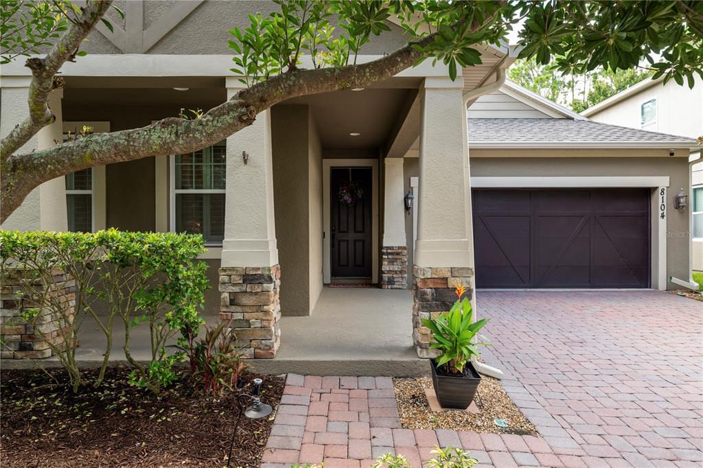 The exterior of a house features a stone-accented porch, a dark front door, and a garage — 8104 JAILENE DRIVE, WINDERMERE, FL