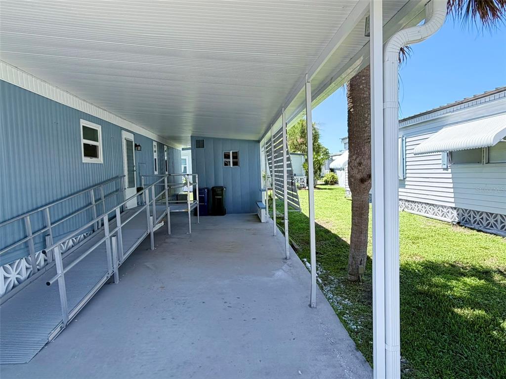 A blue mobile home with a screened-in porch, white brick skirting, and a concrete walkway — 2236 GONDOLA DRIVE, SARASOTA, FL