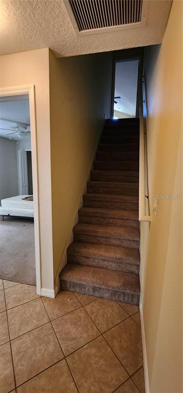 A carpeted staircase leads to an upper level, with a tiled entryway in the foreground — 1134 IVEY LAKE DRIVE, ORANGE CITY, FL