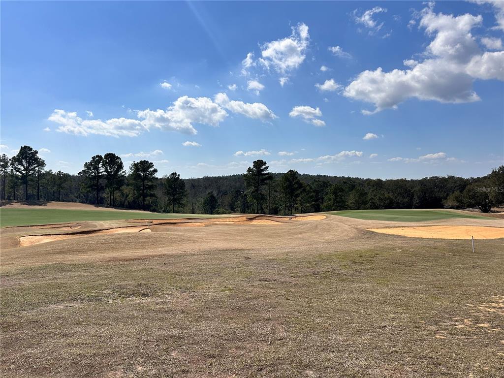 A view of a golf course fairway with sand bunkers and a treeline in distance — 16222 VETTA DRIVE, MONTVERDE, FL
