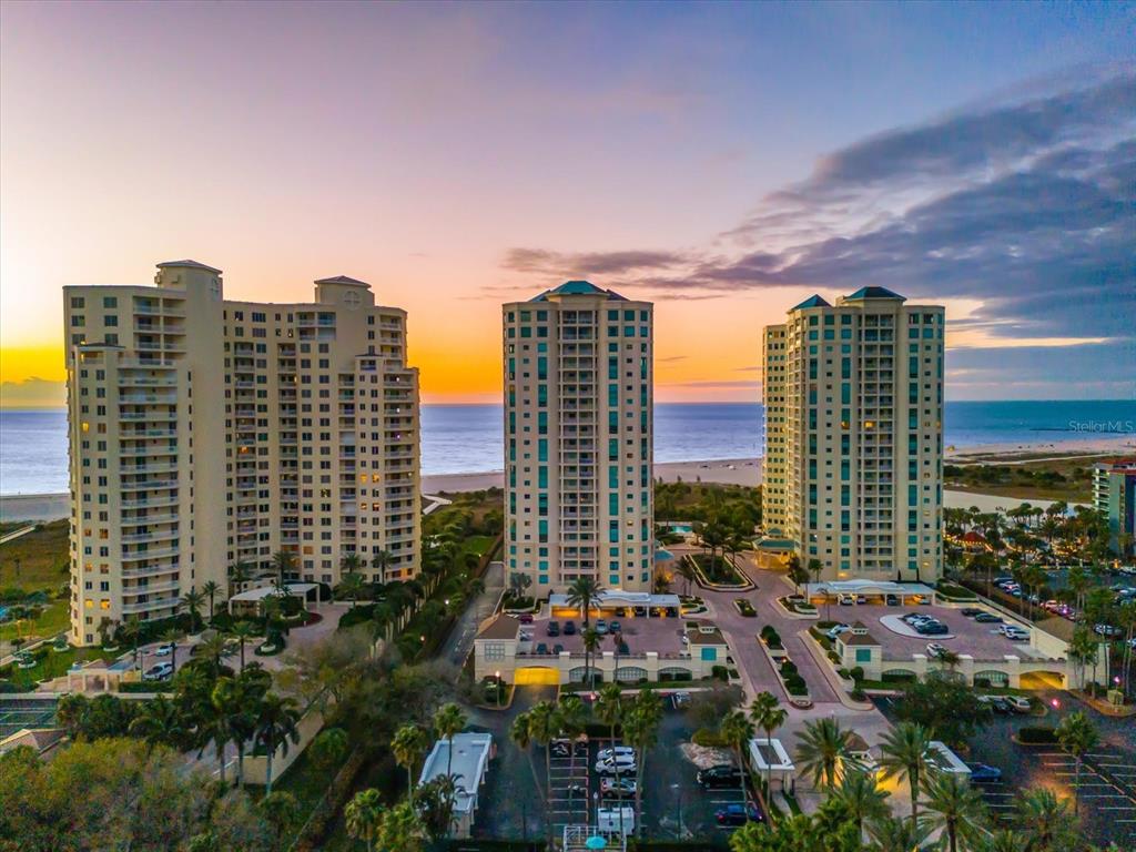 A paved driveway leads to a stone monument sign for The Grande under palm trees — 1180 GULF BOULEVARD UNIT 1504, CLEARWATER, FL