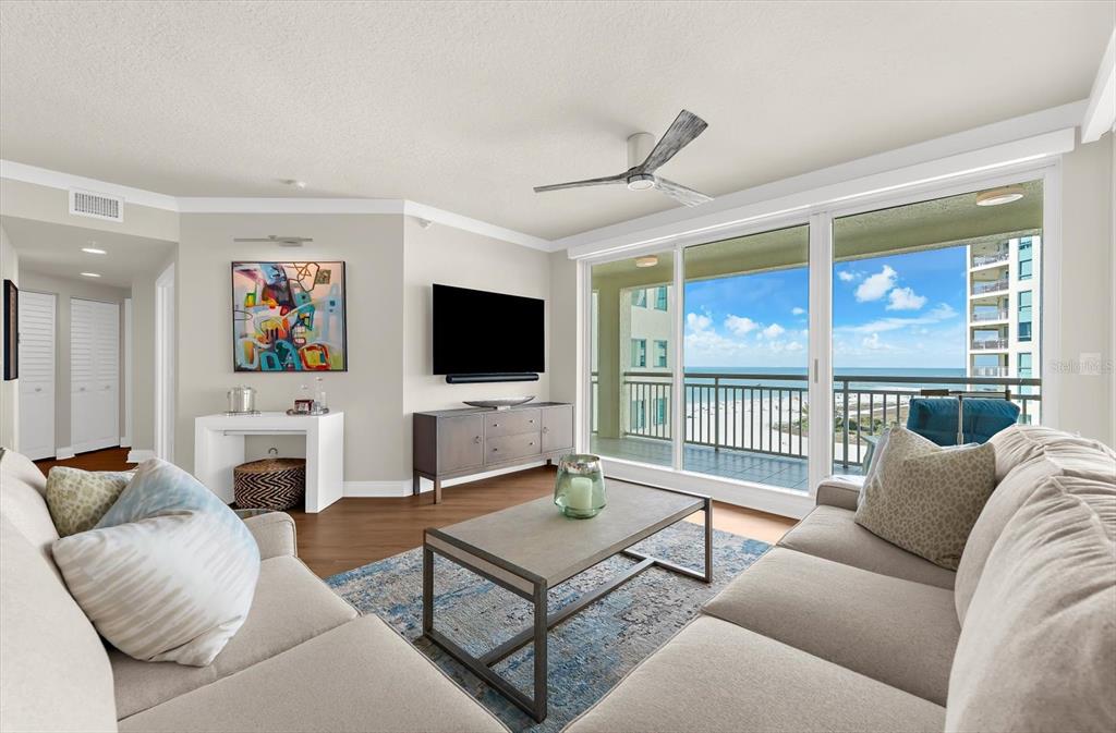 A living room with a sofa, coffee table, television, and a balcony overlooking the ocean — 1180 GULF BOULEVARD UNIT 1504, CLEARWATER, FL