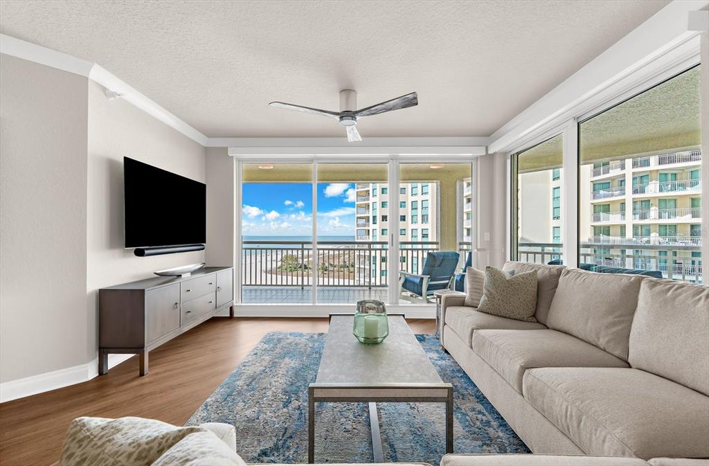 A living room features a beige sofa, a coffee table, and a balcony with ocean views — 1180 GULF BOULEVARD UNIT 1504, CLEARWATER, FL