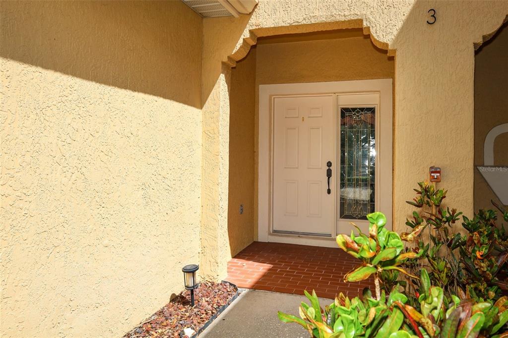 The front entrance features a white door with a glass sidelight and brick flooring — 2247 WEKIVA VILLAGE LANE, APOPKA, FL