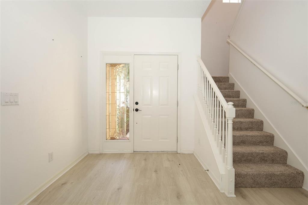 An entryway features light wood-look flooring, a white front door with a sidelight, and stairs — 2247 WEKIVA VILLAGE LANE, APOPKA, FL