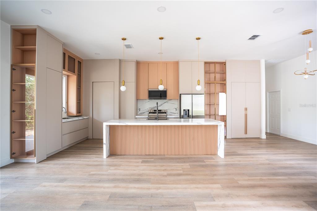A modern kitchen features a slatted wood island, light cabinetry, and marble countertops — 13 NEMESIA COURT E, HOMOSASSA, FL
