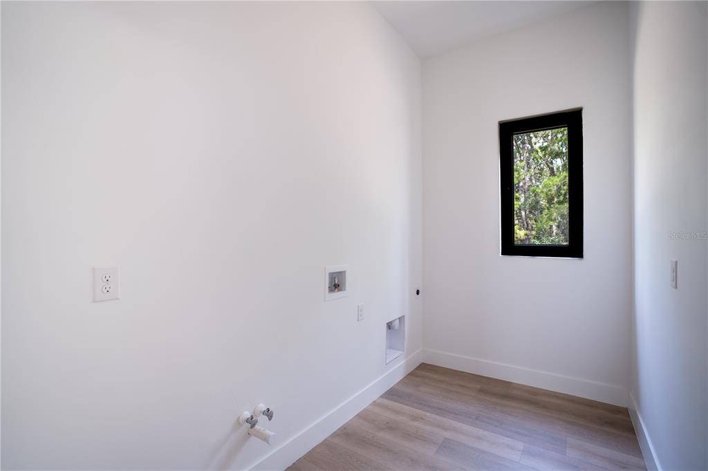 A laundry room with white walls, light wood-look flooring, a window, and utility hookups — 13 NEMESIA COURT E, HOMOSASSA, FL