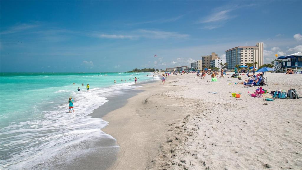A wide, sandy beach with turquoise water, people, and tall buildings in the background — 1802 AUBURN LAKES CIRCLE UNIT 3, VENICE, FL
