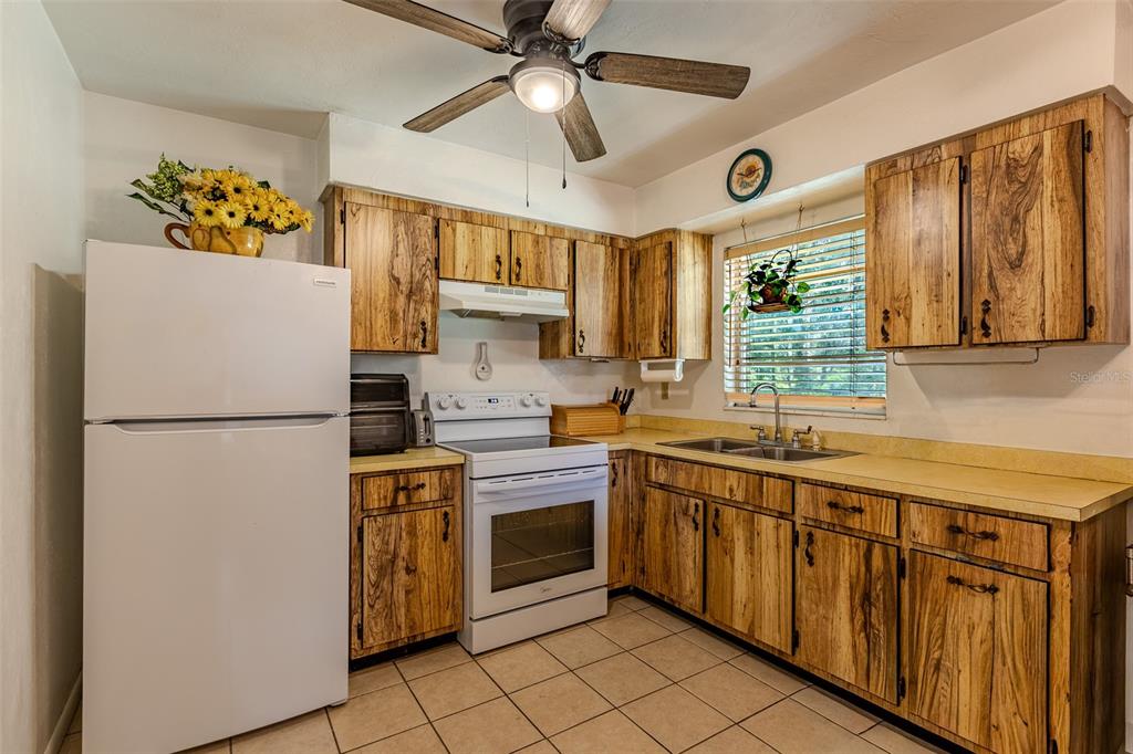 A kitchen features wood-grain cabinets, a white refrigerator, a white stove, and tiled flooring — 17697 NW 222ND STREET, HIGH SPRINGS, FL