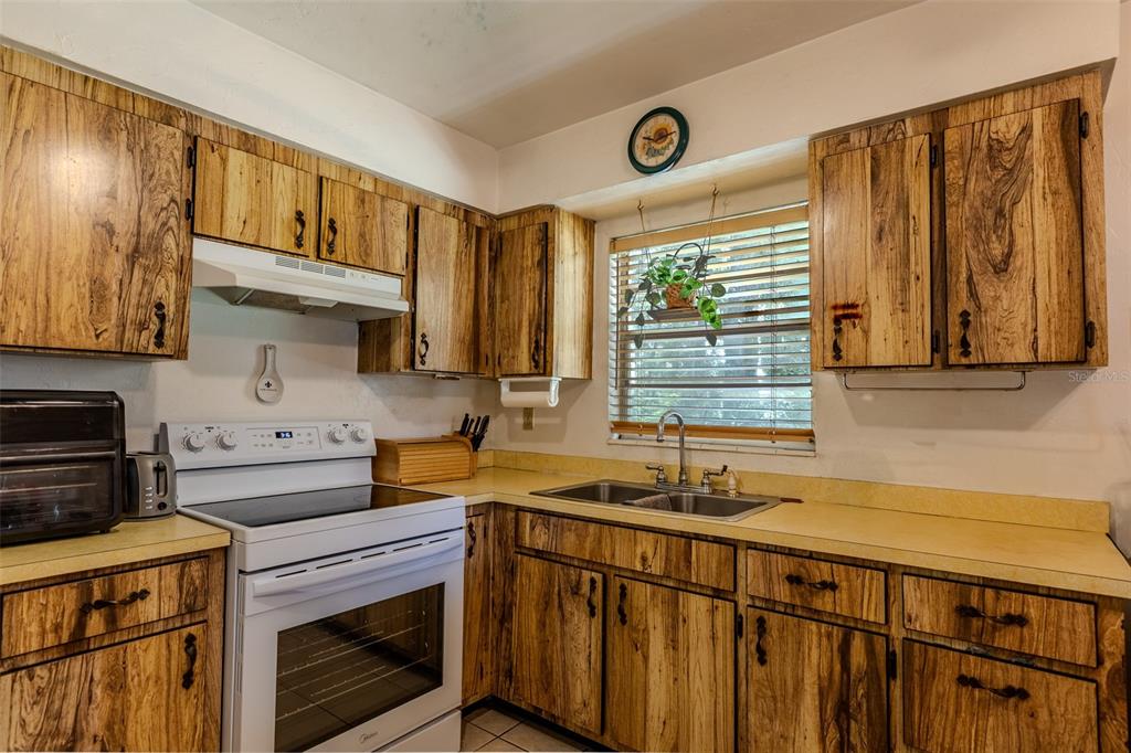 A kitchen features wood-grain cabinets, a white electric range, and a double-basin sink — 17697 NW 222ND STREET, HIGH SPRINGS, FL